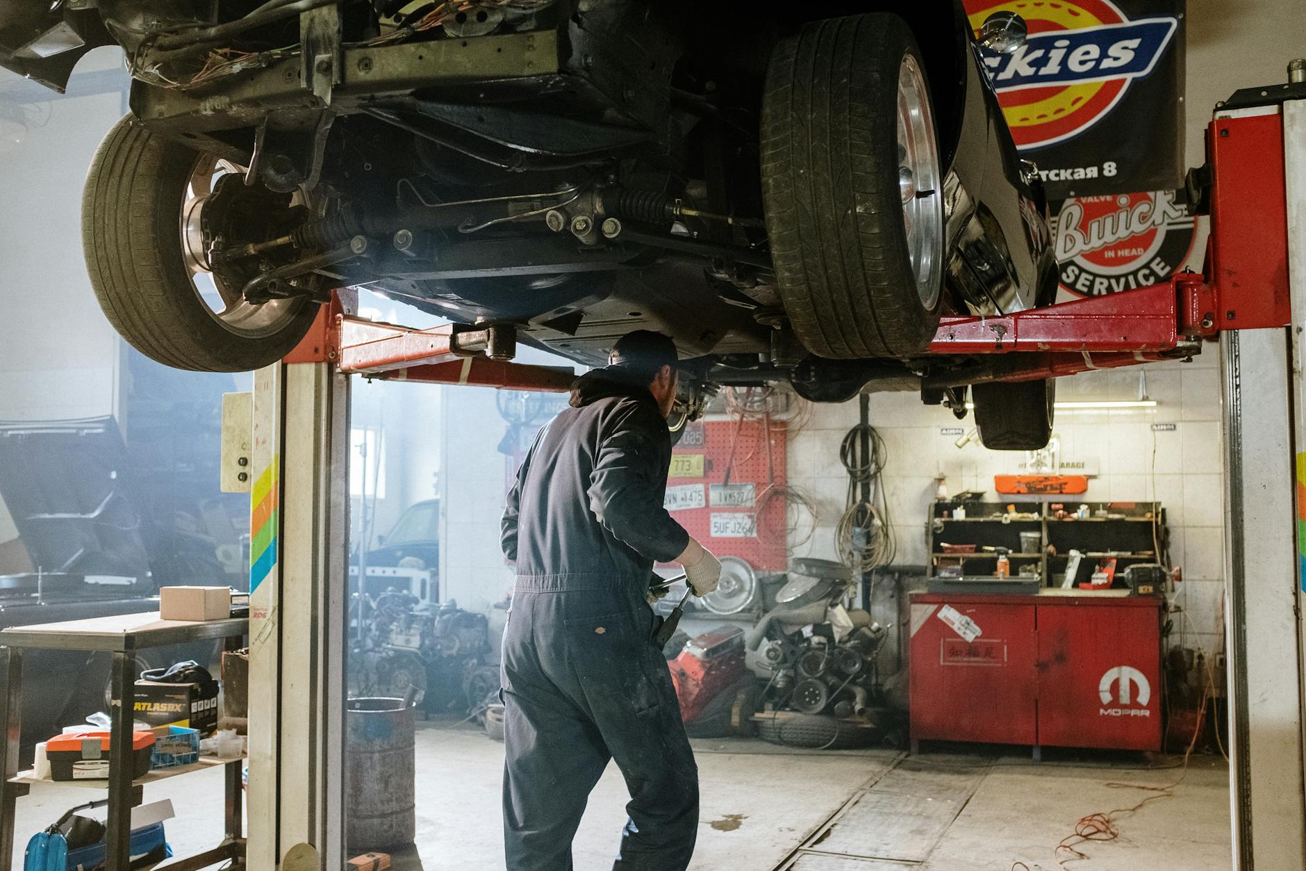 Mechanik naprawiający zawieszenie auta w warsztacie samochodowym