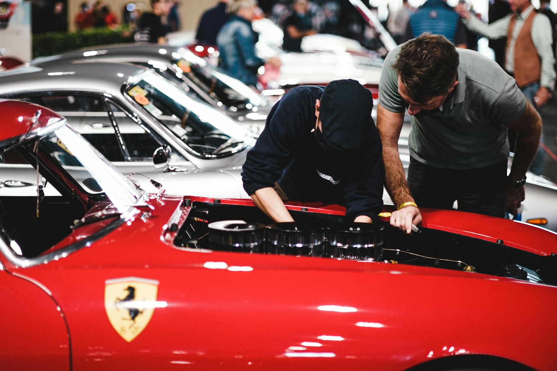 Mechanicy oglądają silnik czerwonego Ferrari na zlocie klasycznych aut