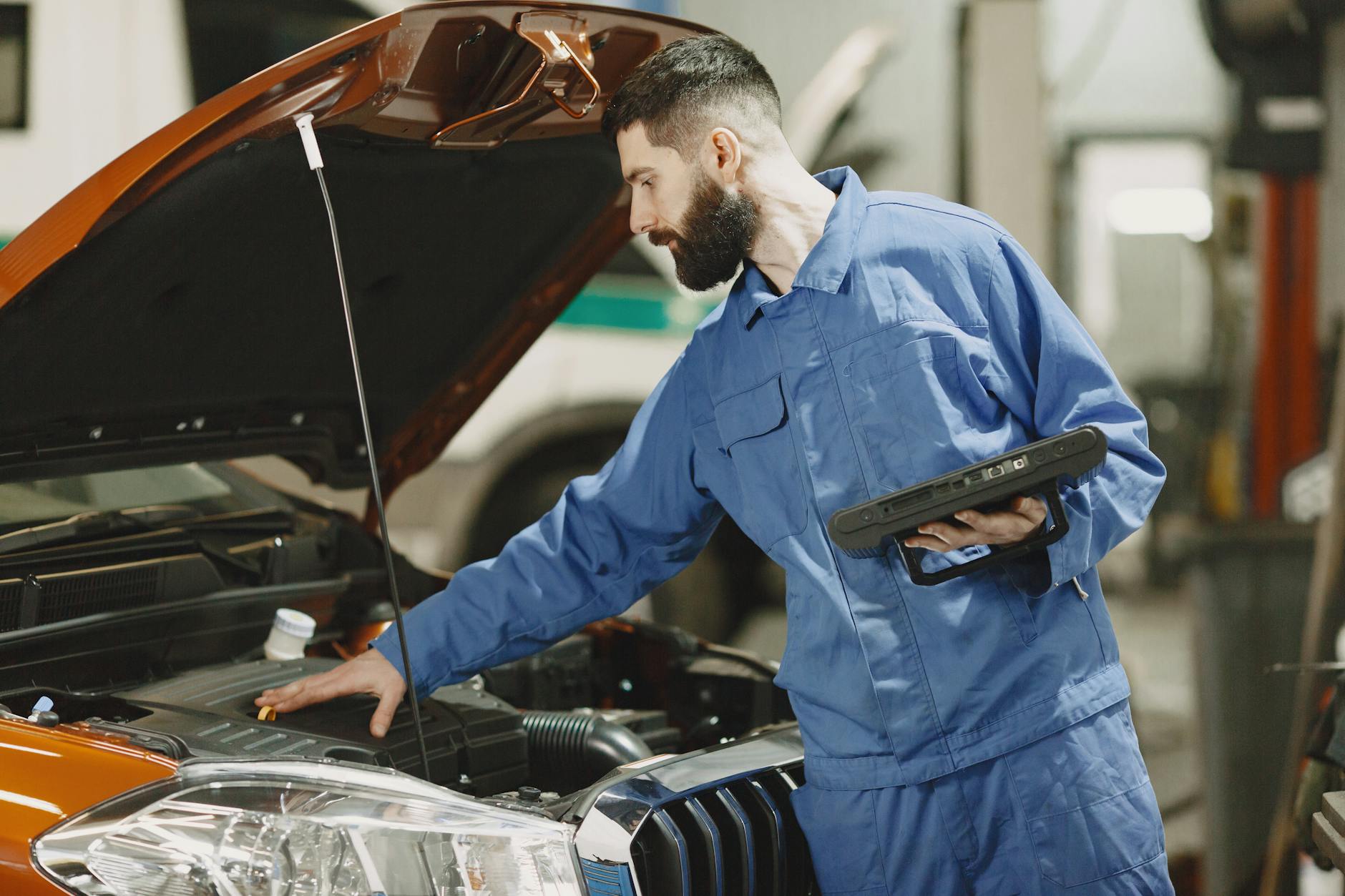 Mechanik w garażu ogląda pracę silnika Mazdy 5 pod otwartą maską