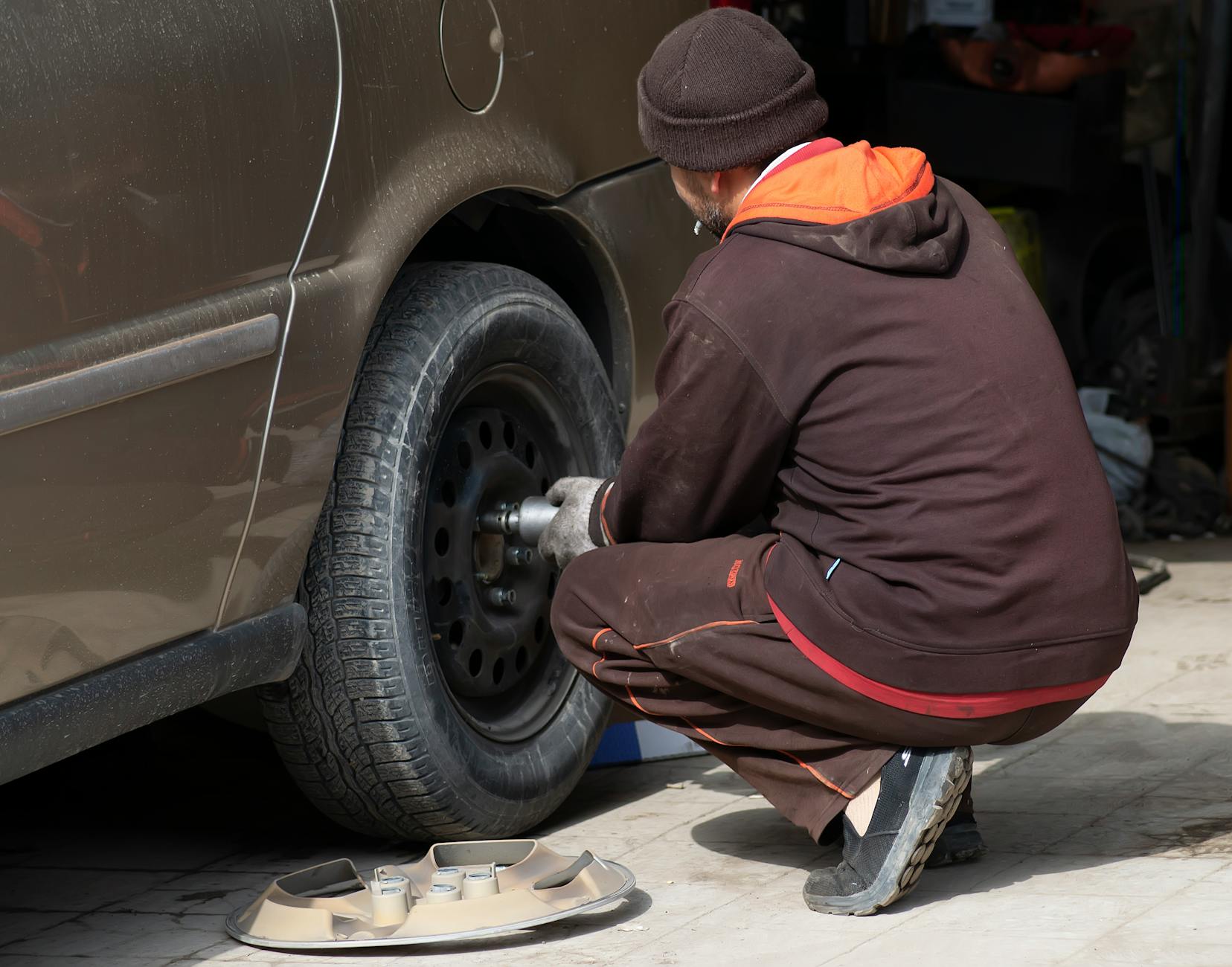 Mechanik przy kole samochodu w warsztacie podczas naprawy Mechanik przy kole samochodu w warsztacie podczas naprawy