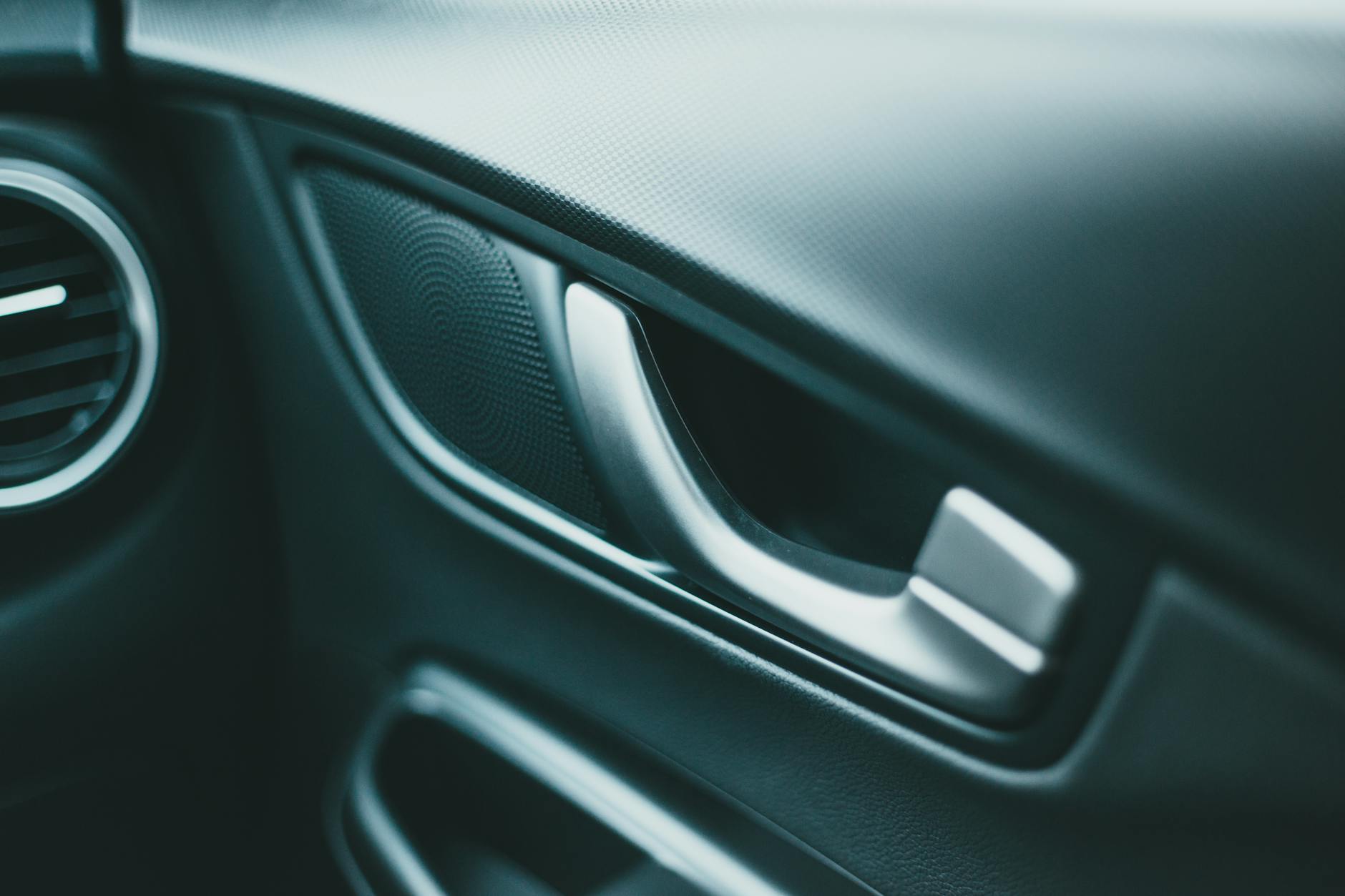 Zbliżenie na panel drzwi Mazdy z głośnikiem i chromowaną klamką